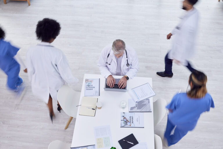 Doctor, man and laptop in busy hospital for medicine research, surgery schedule management or medic.