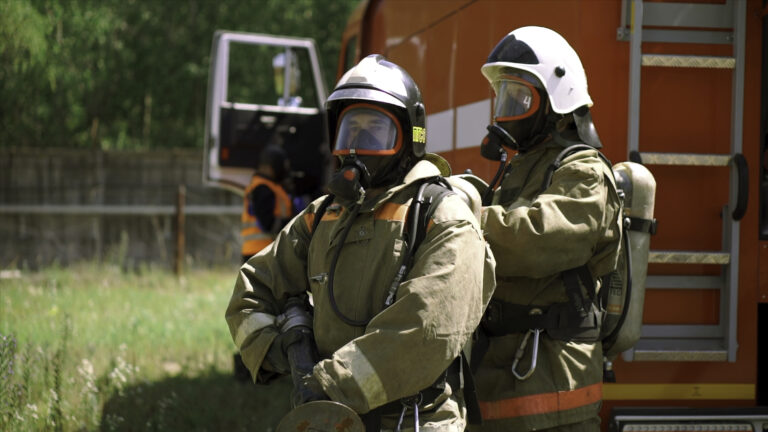 Firefighters on street in summer. Clip. Cinematic view of firefighters standing by car on hot day. Firefighters in uniforms came to call.