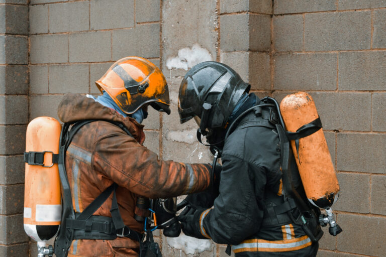 Barcelona, Cataluña, Spain - January 24, 2022: Group of firefighters preparing the rescue of a victim. They are  equipped with heavy respiratory protection and wears protective equipment that protects them from the heat and flames.