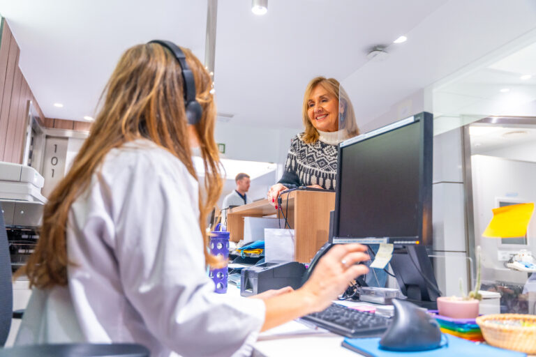 Receptionist of an hospital attending a mature woman standing in front the desk